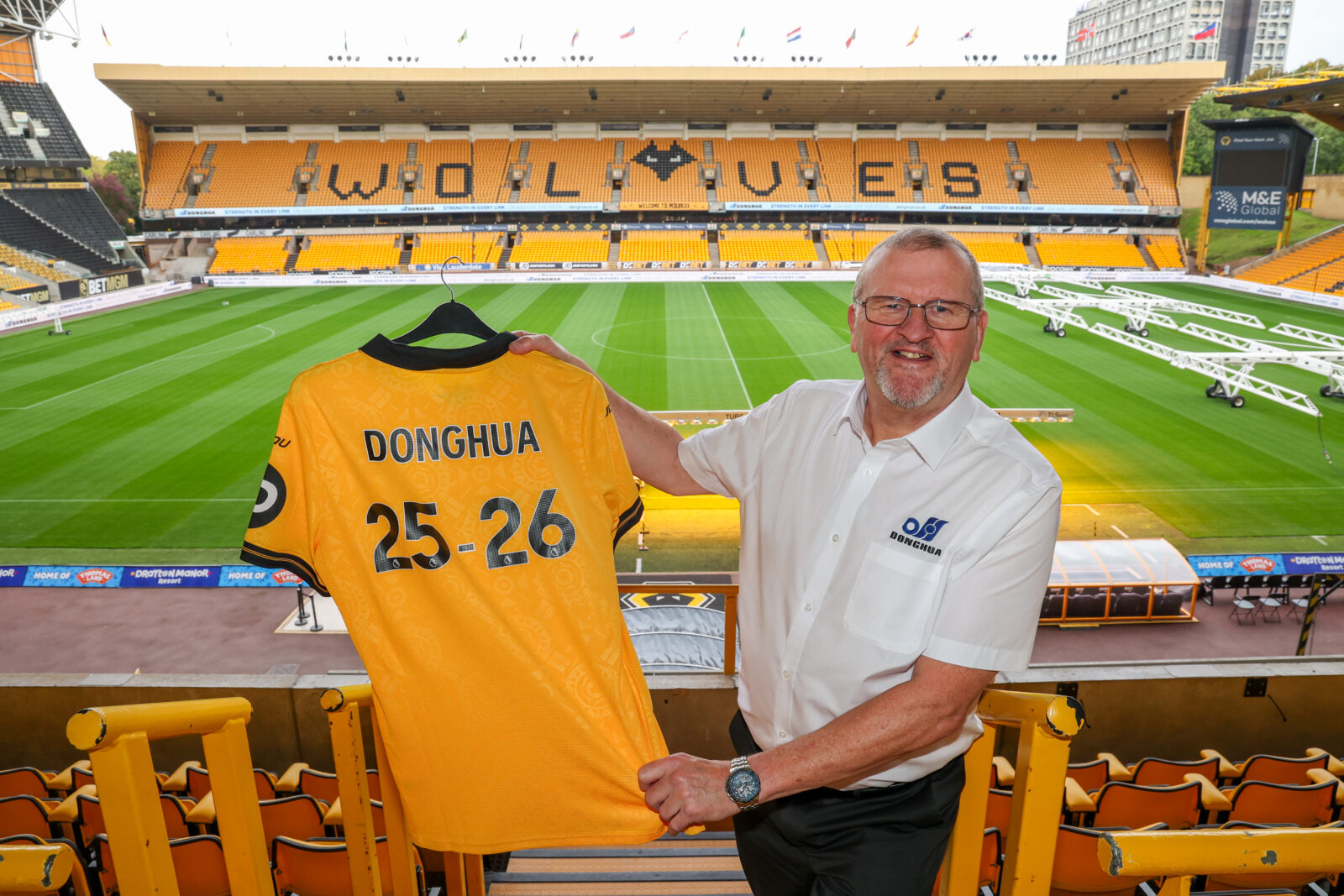 Wolves Business Partner - Bob Wellsbury standing in directors box holding Donghua branded football shirt